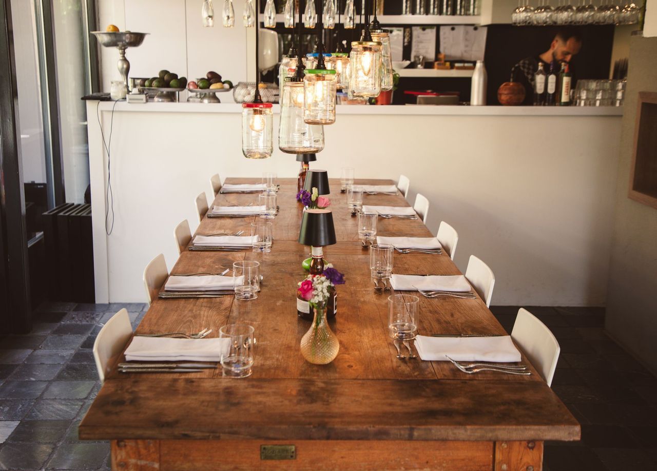 Lange houten eettafel met hanglampen, ideaal voor gasten.