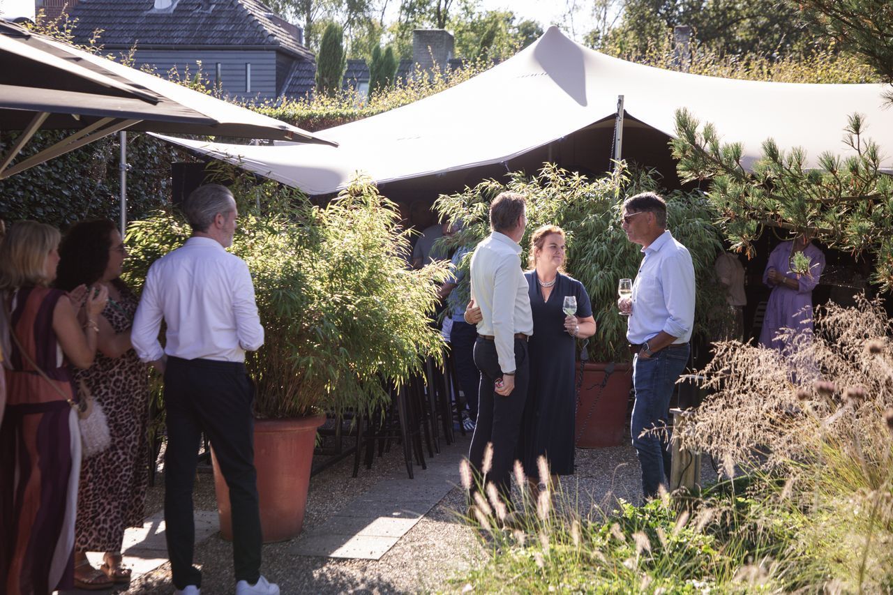 Mensen die buiten bij een tent samenkomen, in de setting van een tuinfeest.