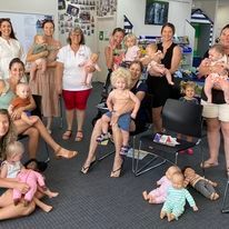 Loretta standing in the middle of adults with babies and children