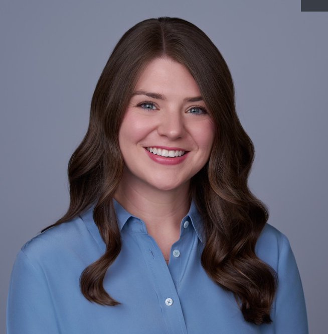 A woman in a blue shirt is smiling for the camera