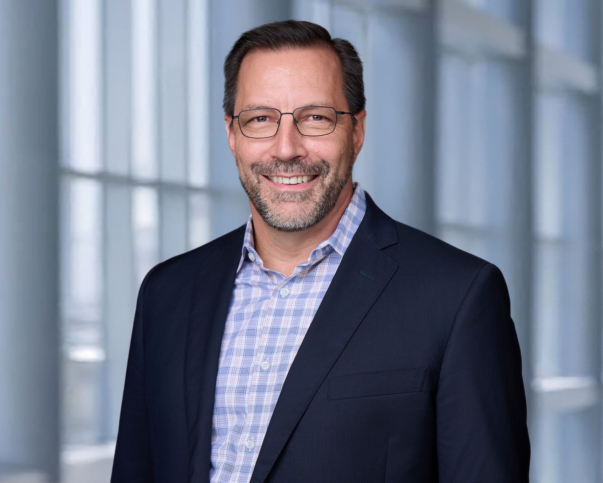 A man in a suit and glasses is smiling for the camera.