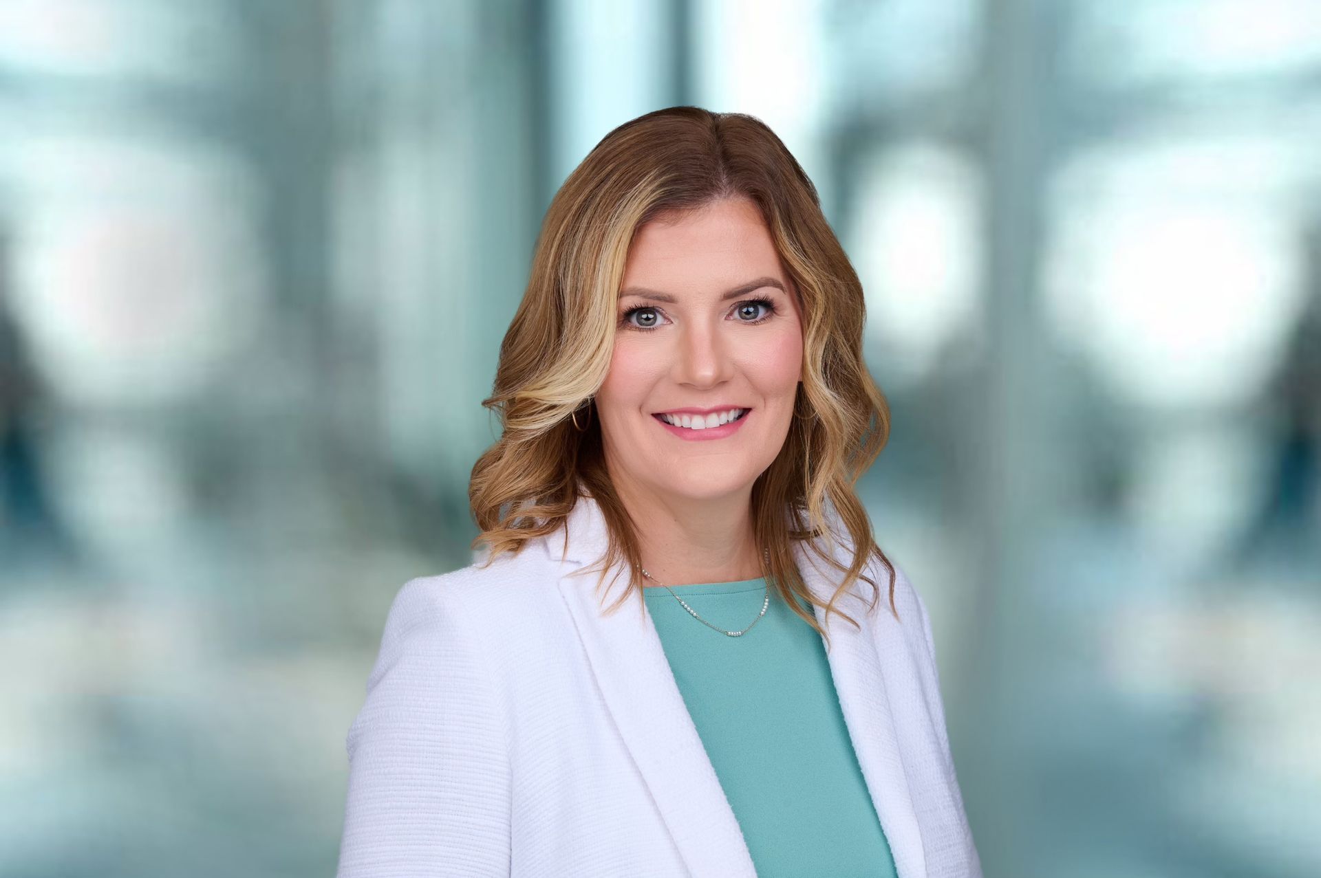 A woman in a white jacket and green shirt is smiling for the camera.