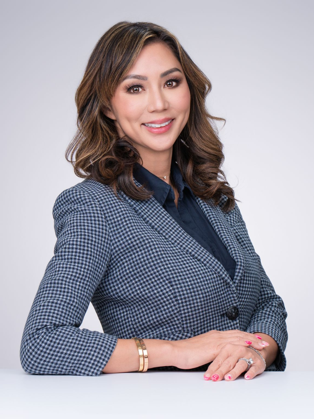 Smiling professional in gray blazer seated against a light background