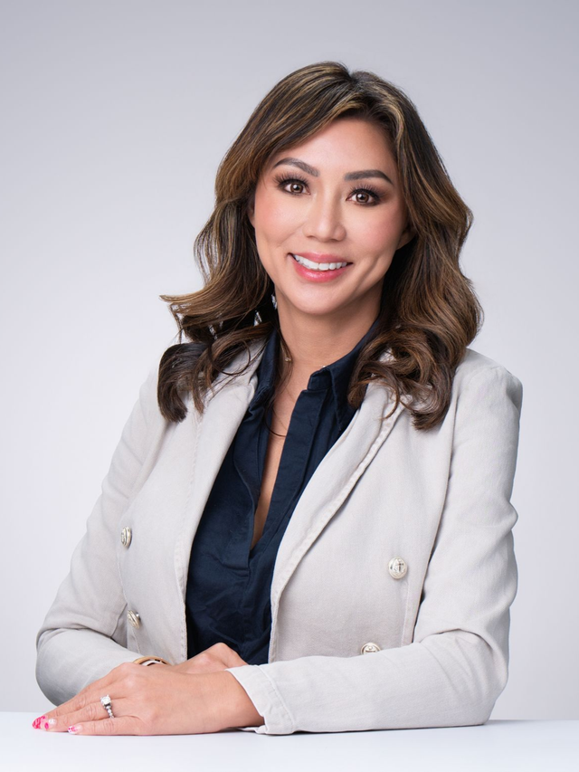 Professional woman in a light gray blazer smiling against a plain background