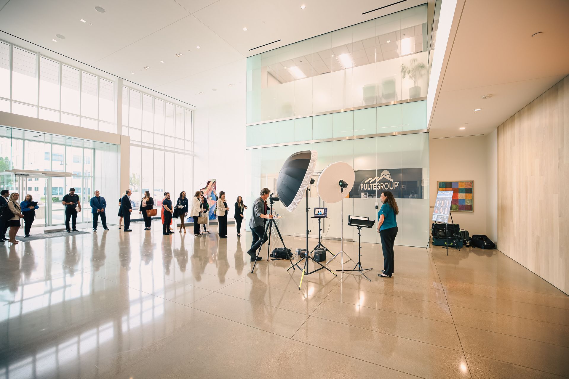 A group of people are standing in a large room with a lot of windows.