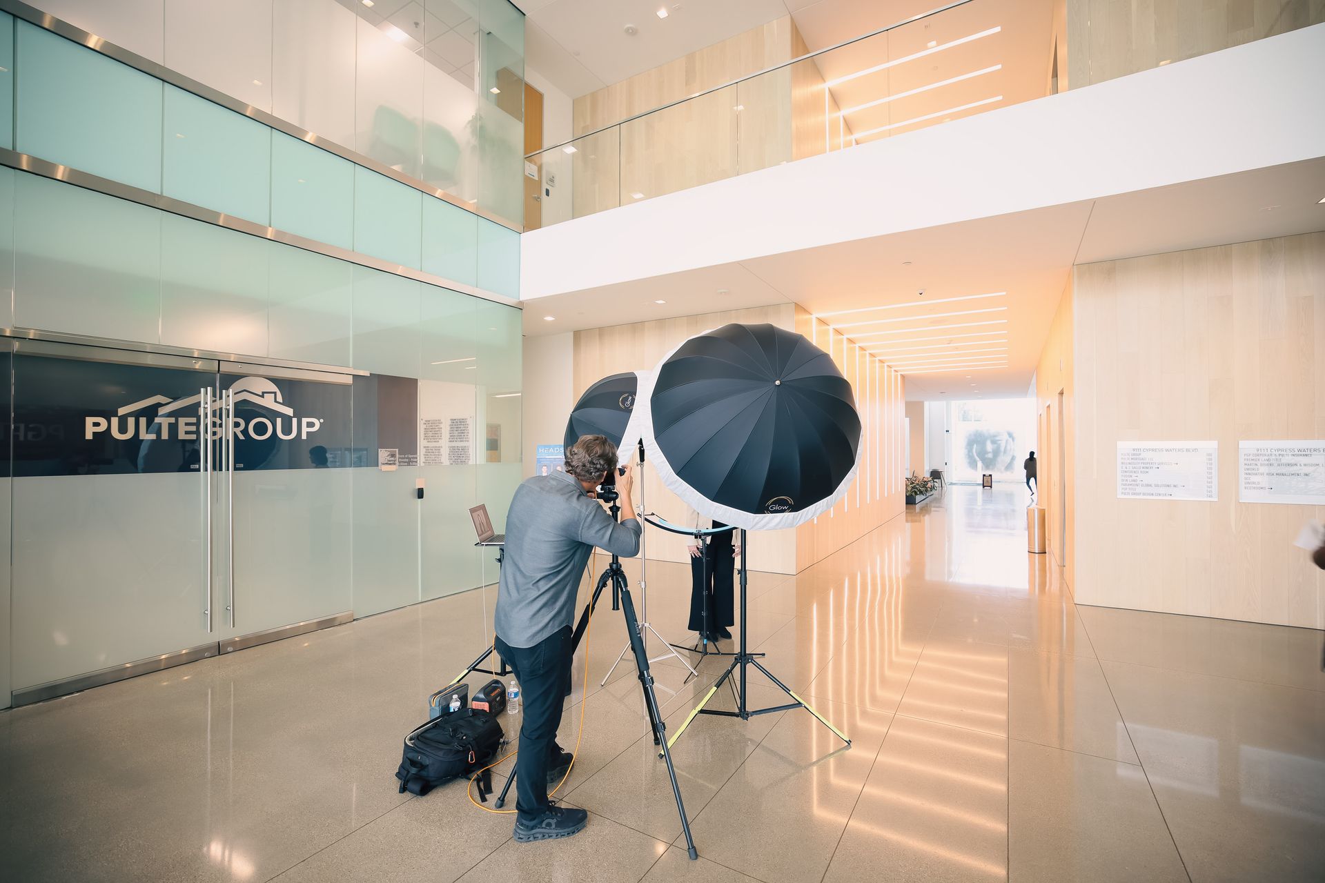 A man is standing in a hallway taking a picture with an umbrella.