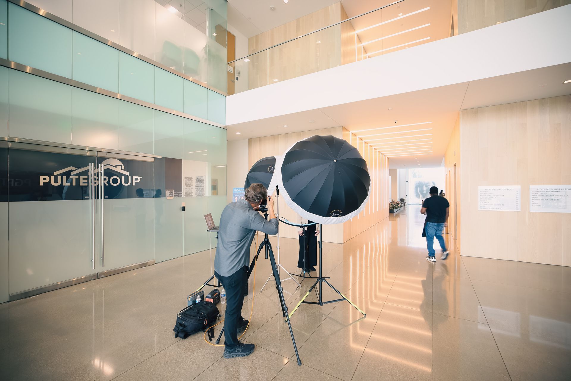 A man is taking a picture of a woman with an umbrella in a lobby.