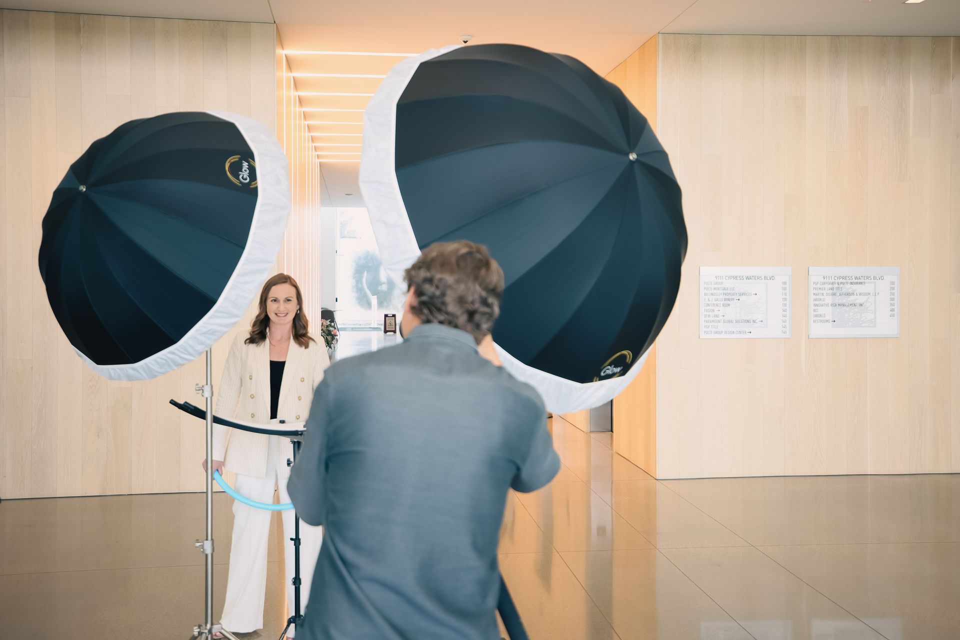 A man is taking a picture of a woman with two umbrellas.