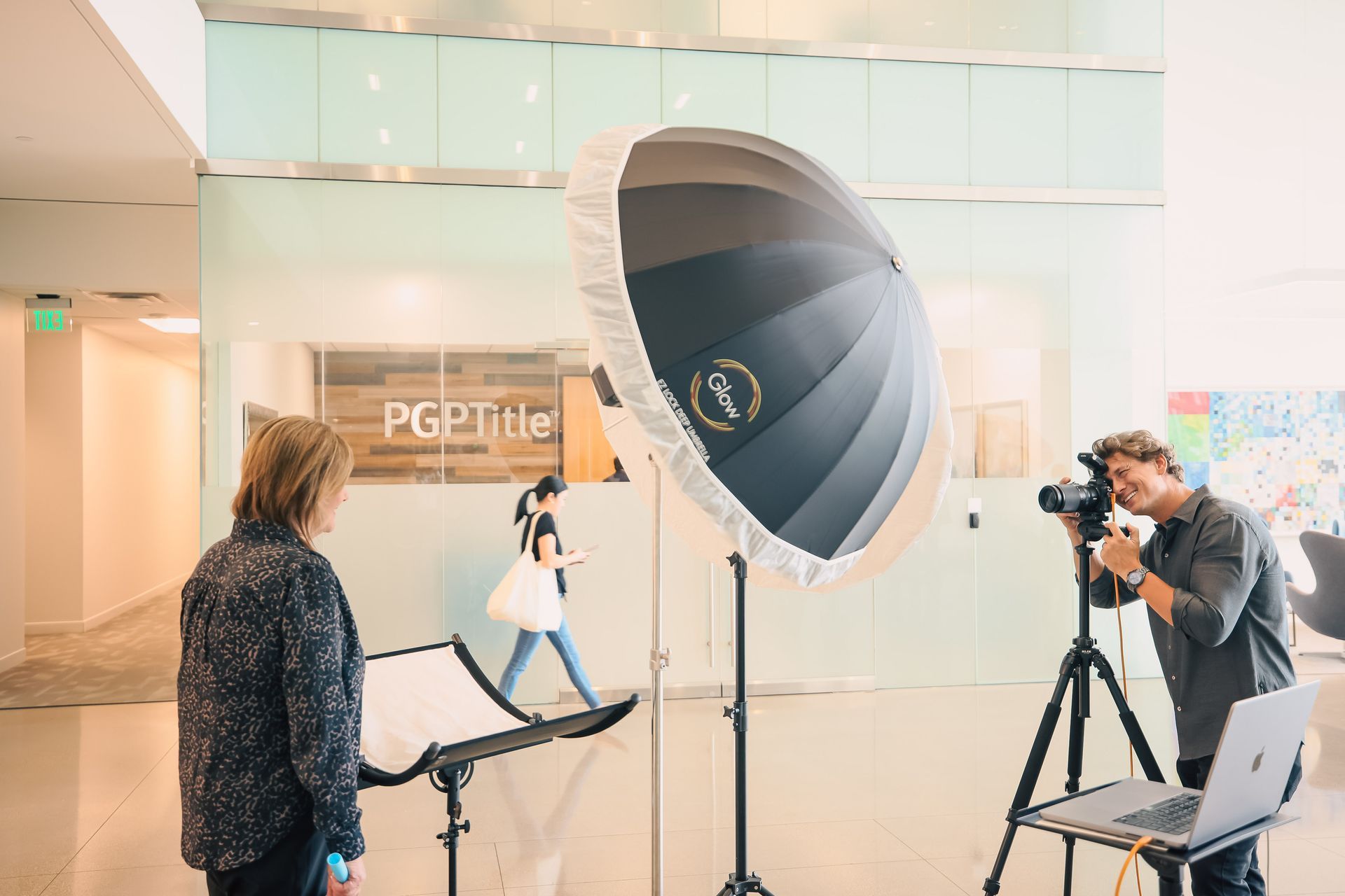 A man is taking a picture of a woman in front of a camera.