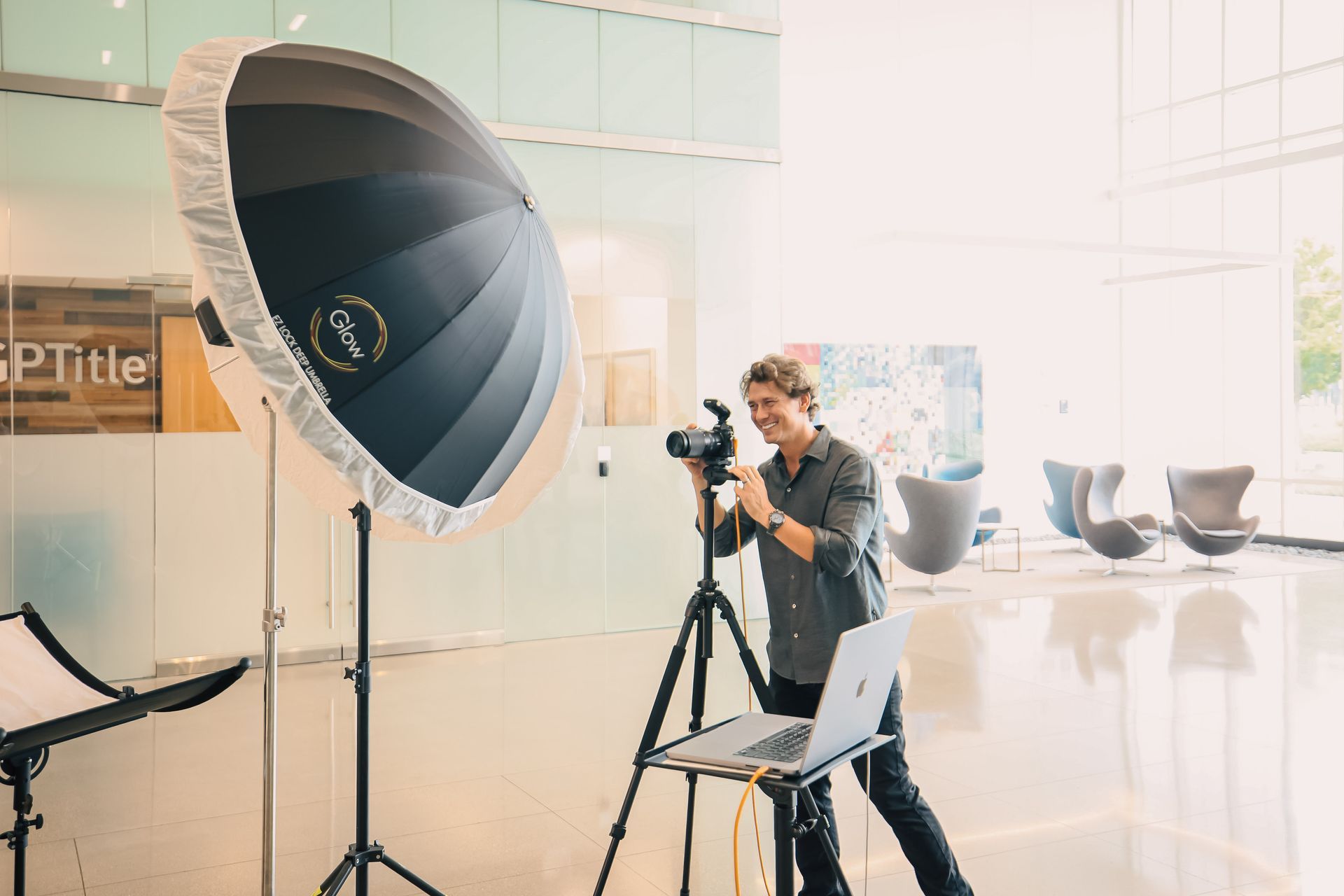 A man is taking a picture with a camera and a laptop.