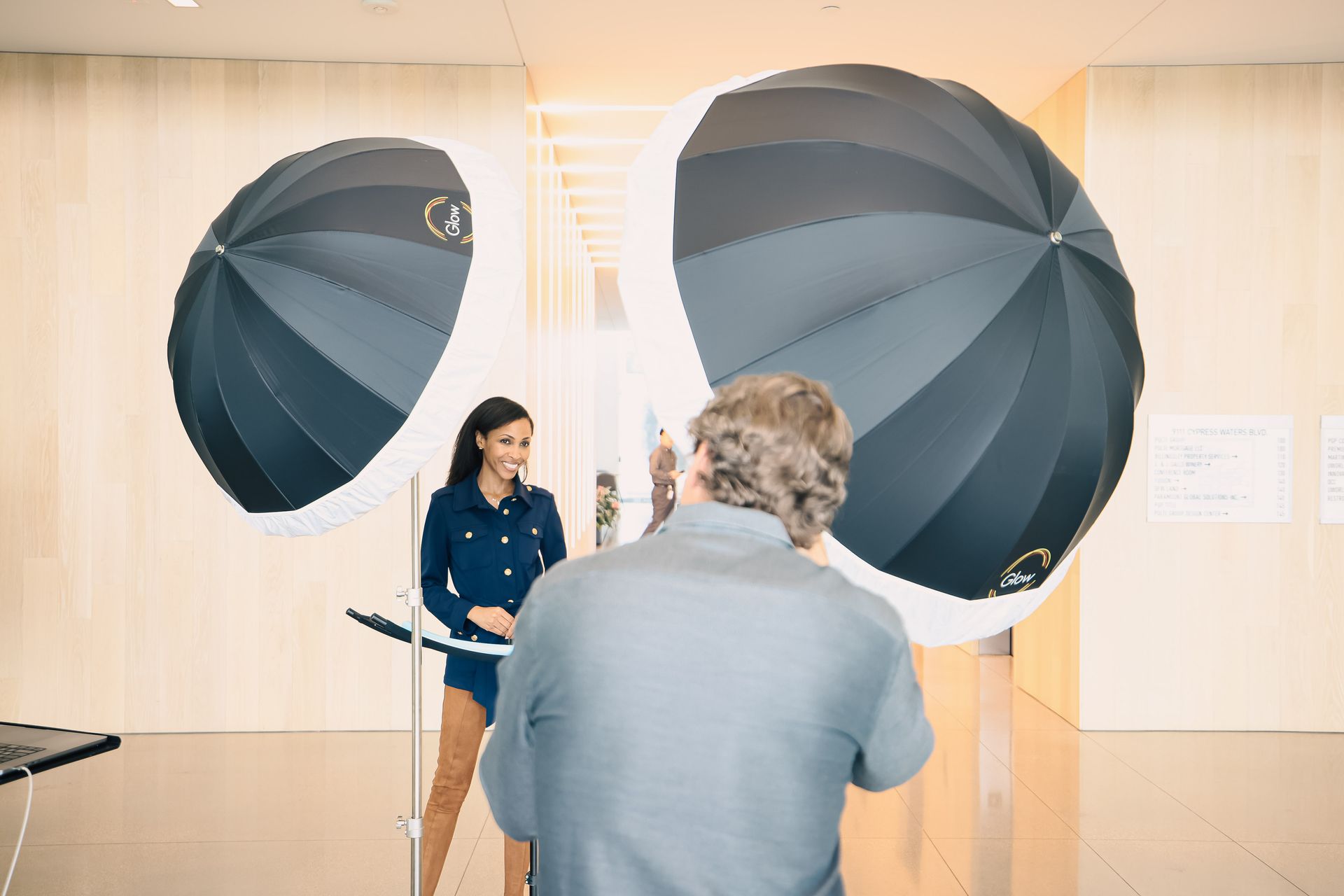 A man is taking a picture of a woman in front of two umbrellas.