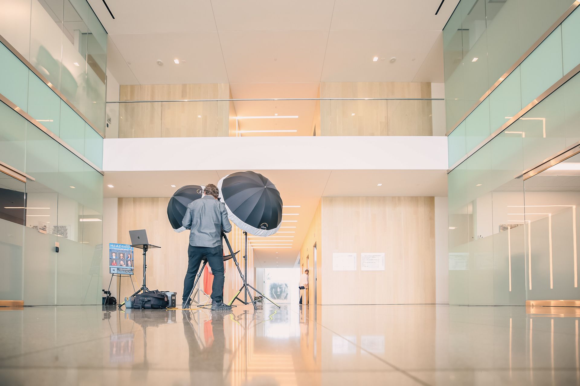 A man is standing in a hallway with umbrellas and a camera.