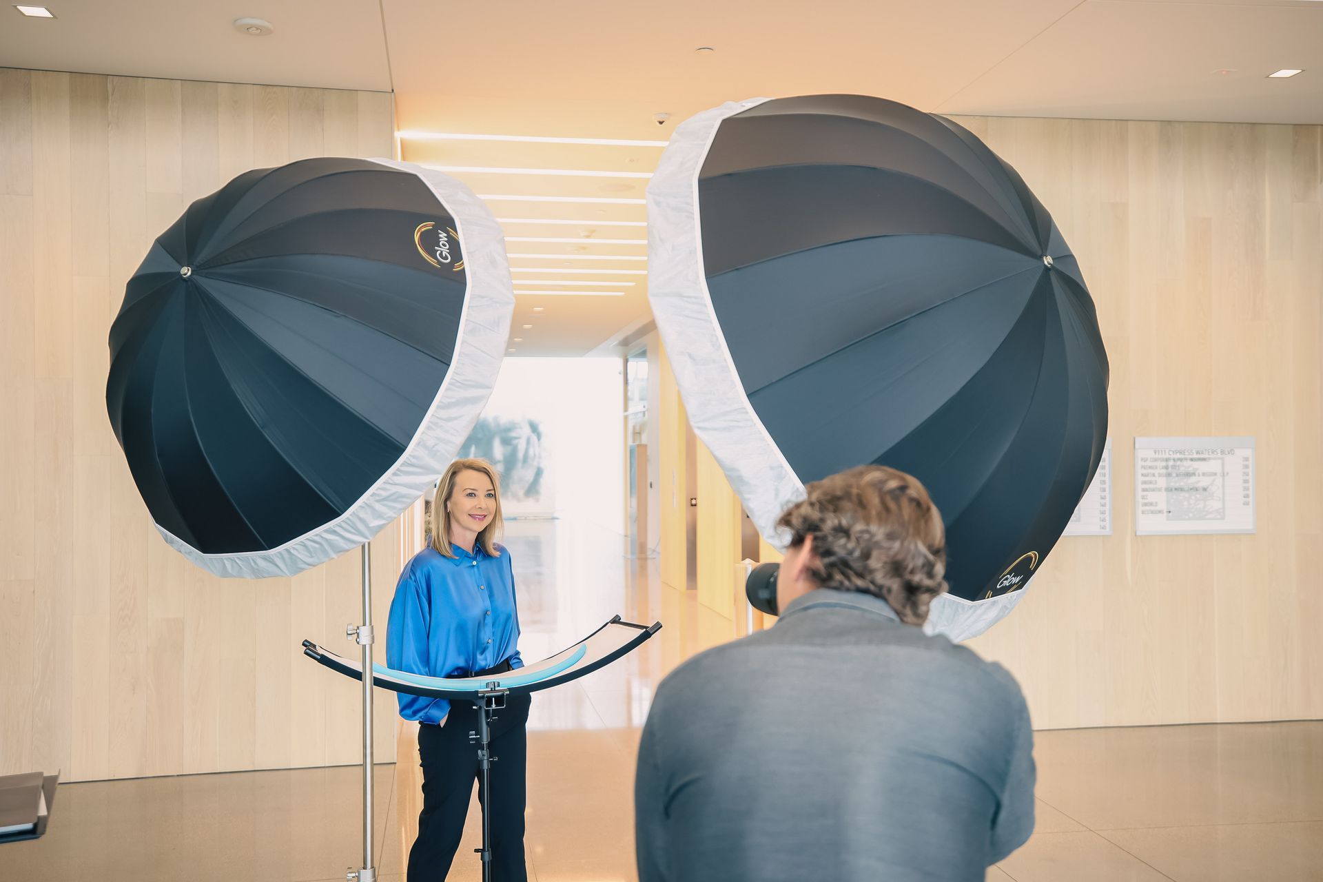 A man is taking a picture of a woman in front of two umbrellas.