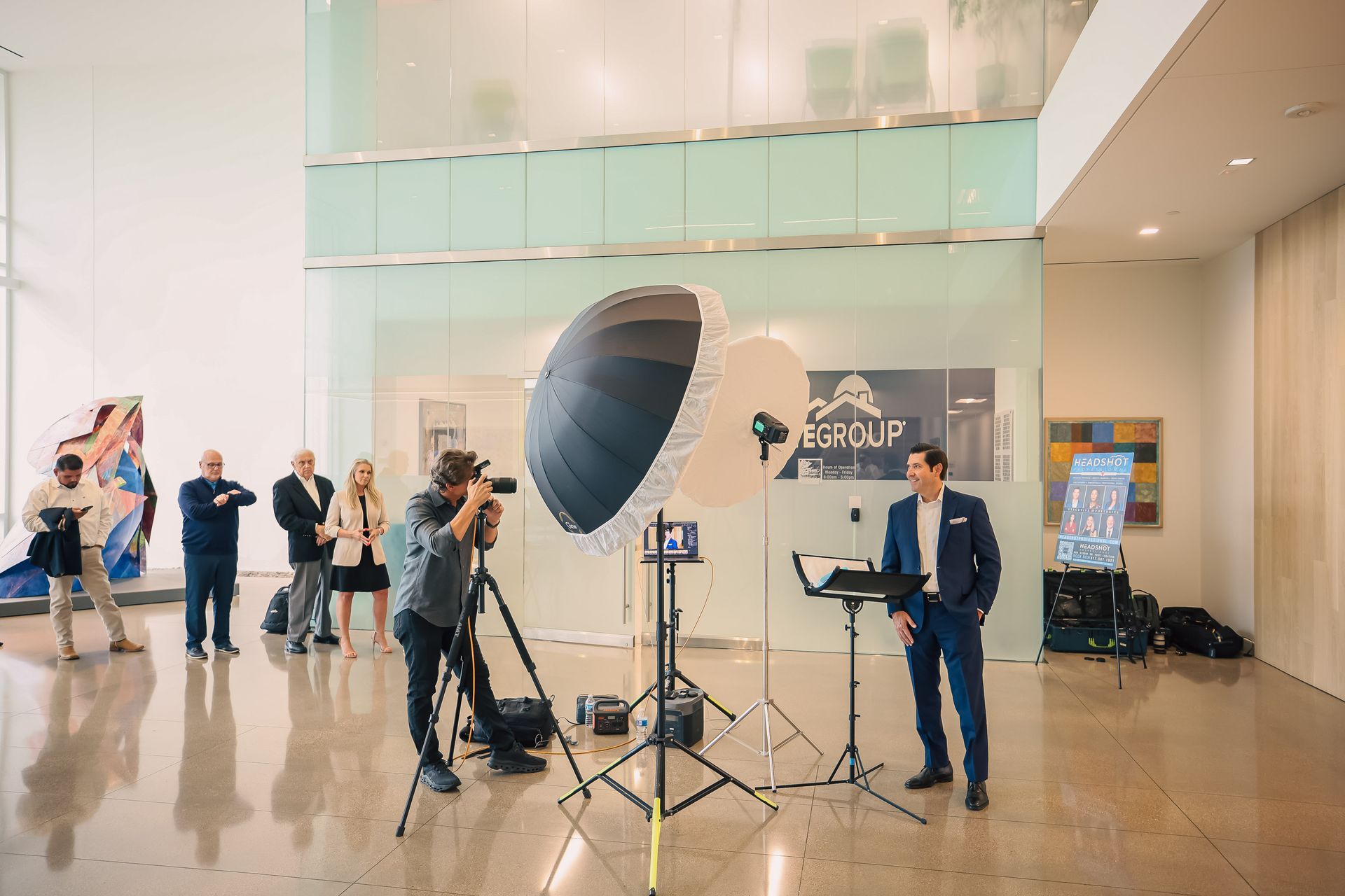 A group of people are taking a picture of a man in a suit in a lobby.