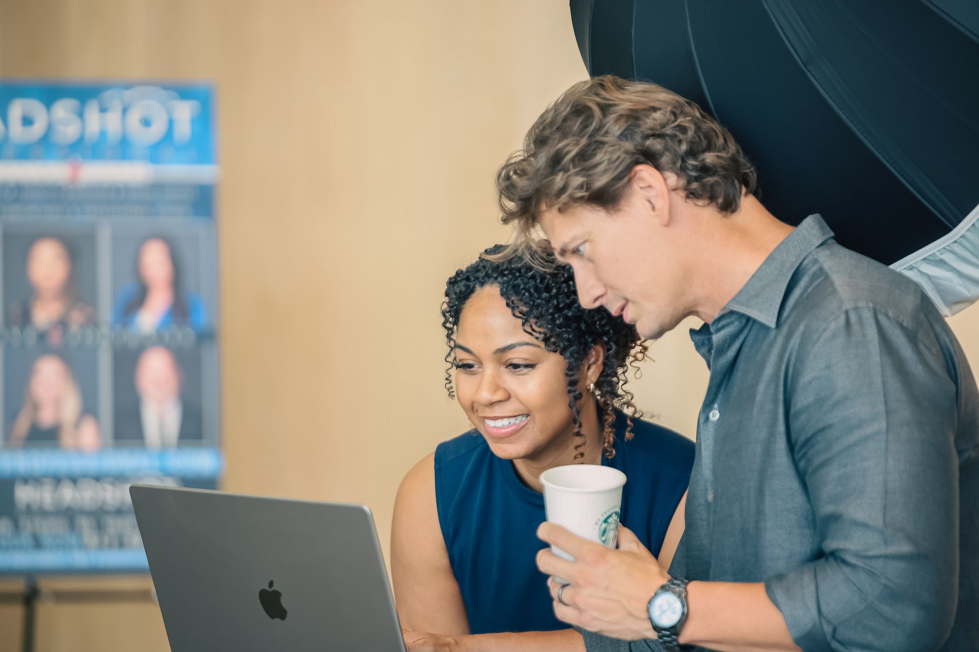 A man and a woman are looking at a laptop computer.