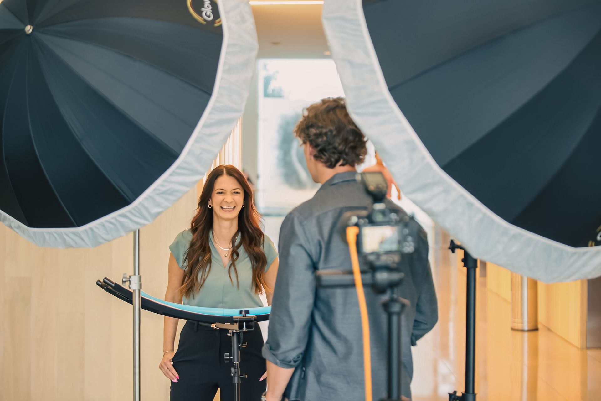 A man is taking a picture of a woman in front of a camera.
