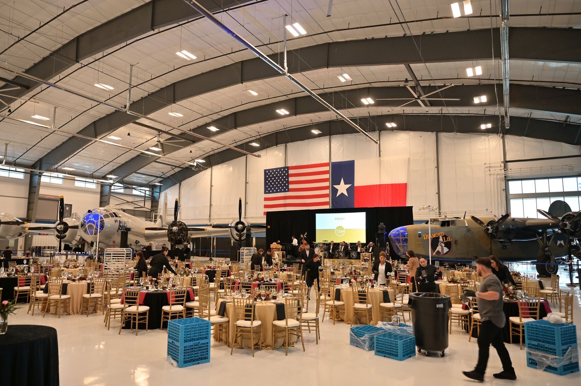 A large room filled with tables and chairs and a large american flag.