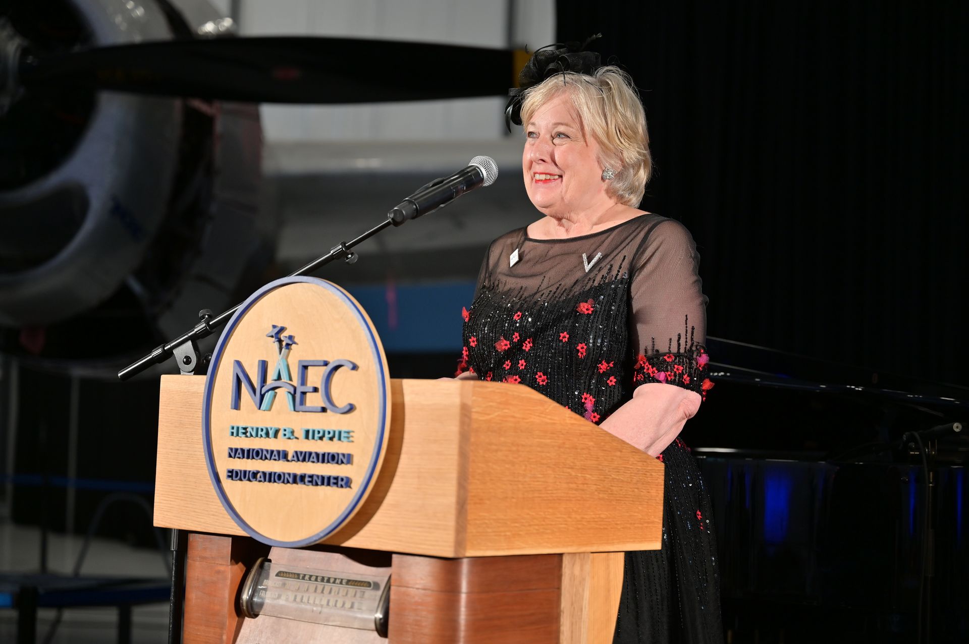 A woman is standing at a podium with a naec logo on it