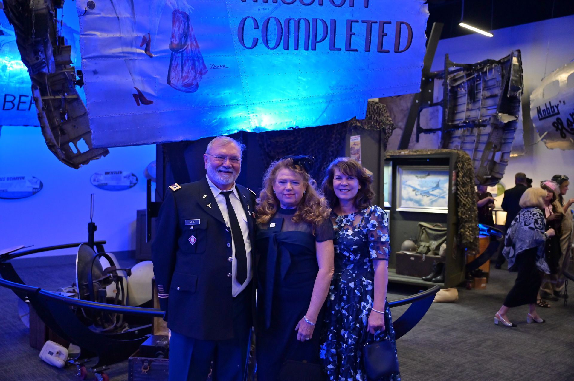 A man and two women are posing for a picture in front of a sign that says completed.