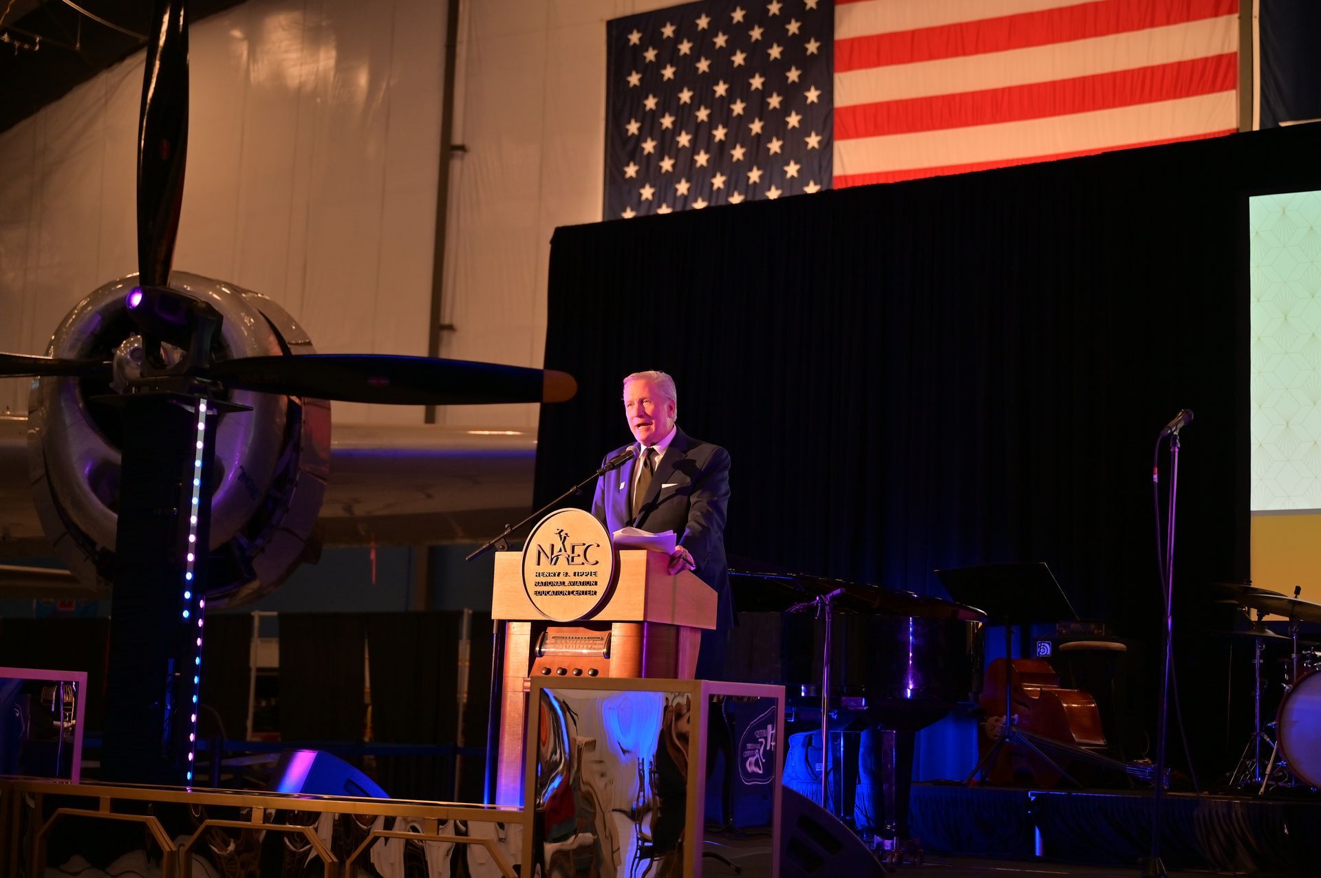 A man is standing at a podium giving a speech in front of an american flag.