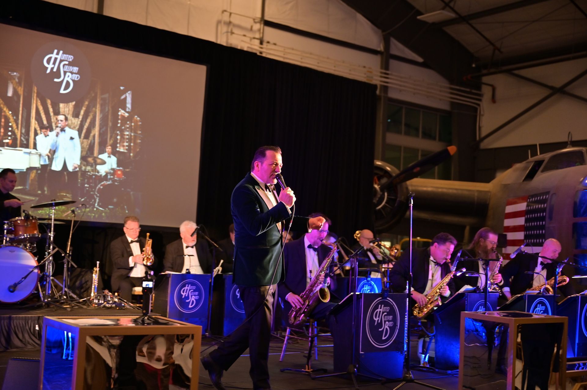 A man is singing into a microphone in front of an orchestra.