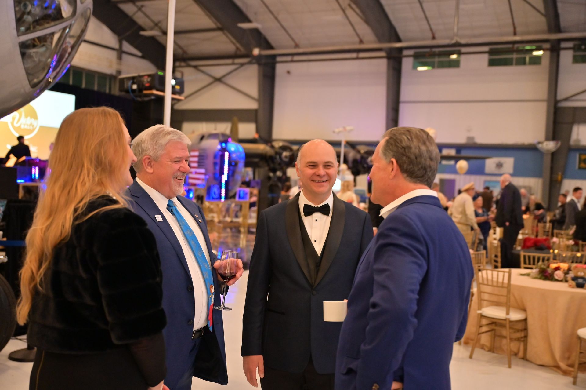 A group of people are standing in a room talking to each other.