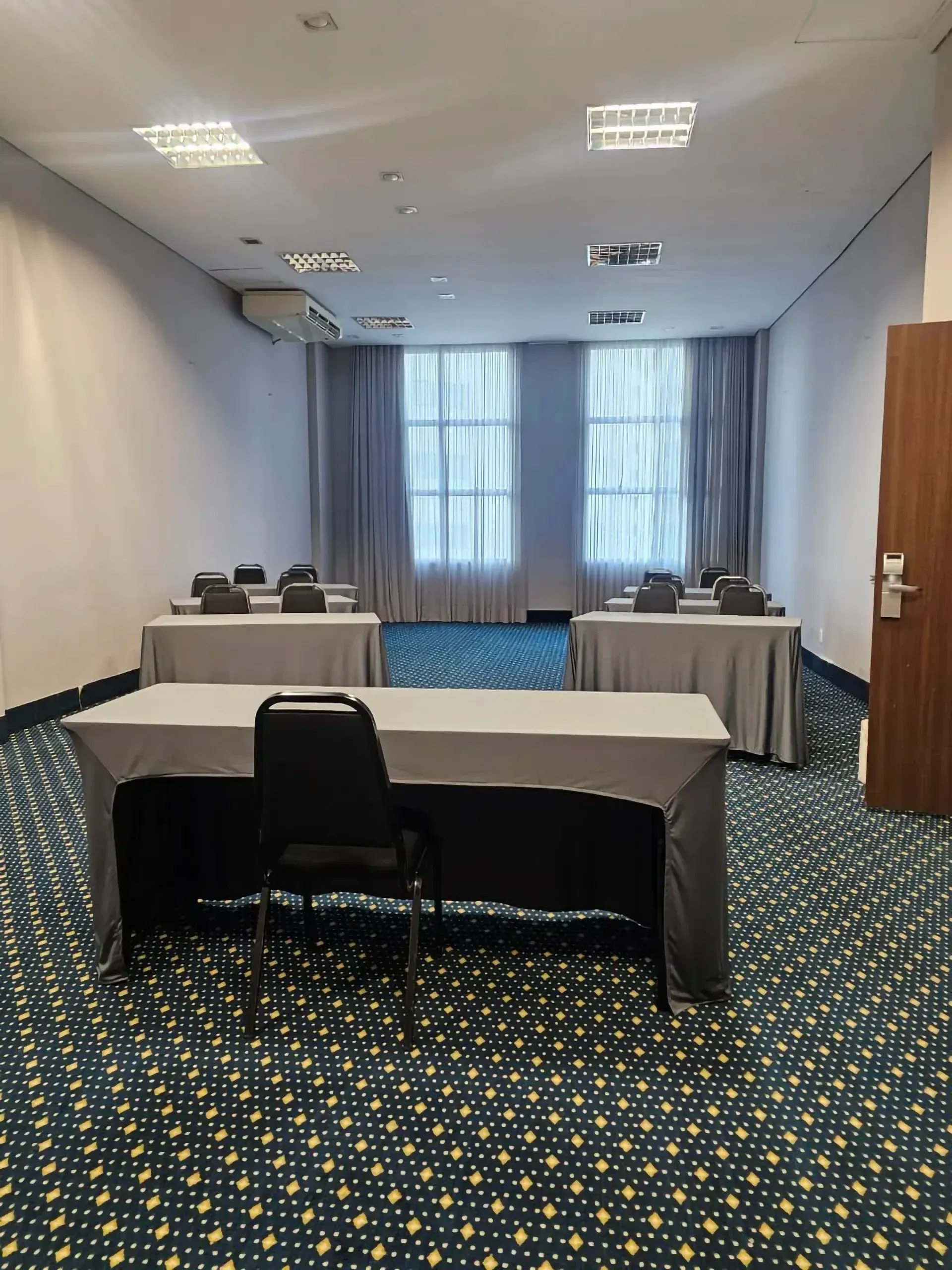 Uma sala de conferências com mesas e cadeiras e um tapete azul.