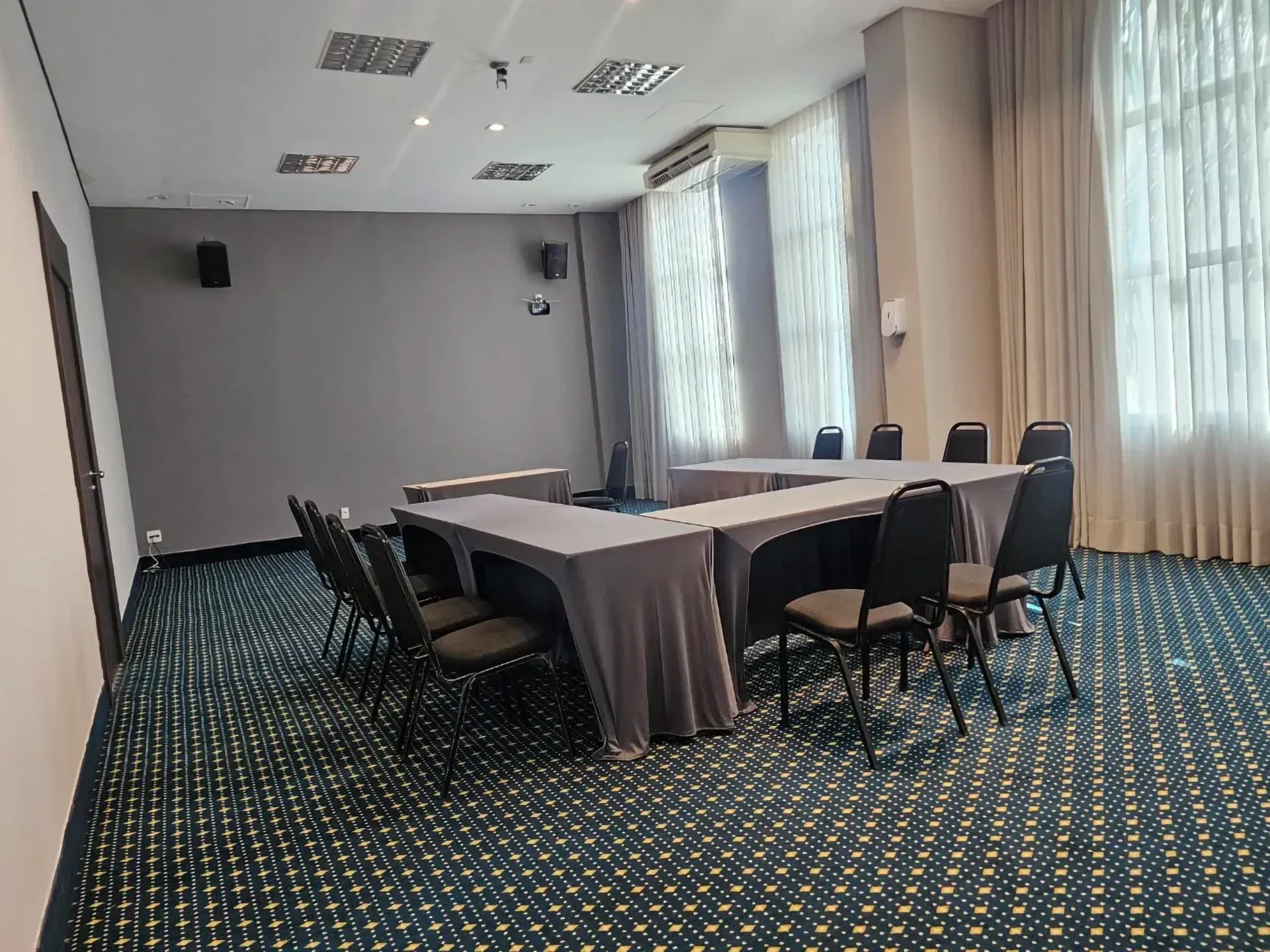 Uma sala de conferências com mesas e cadeiras e um tapete verde.