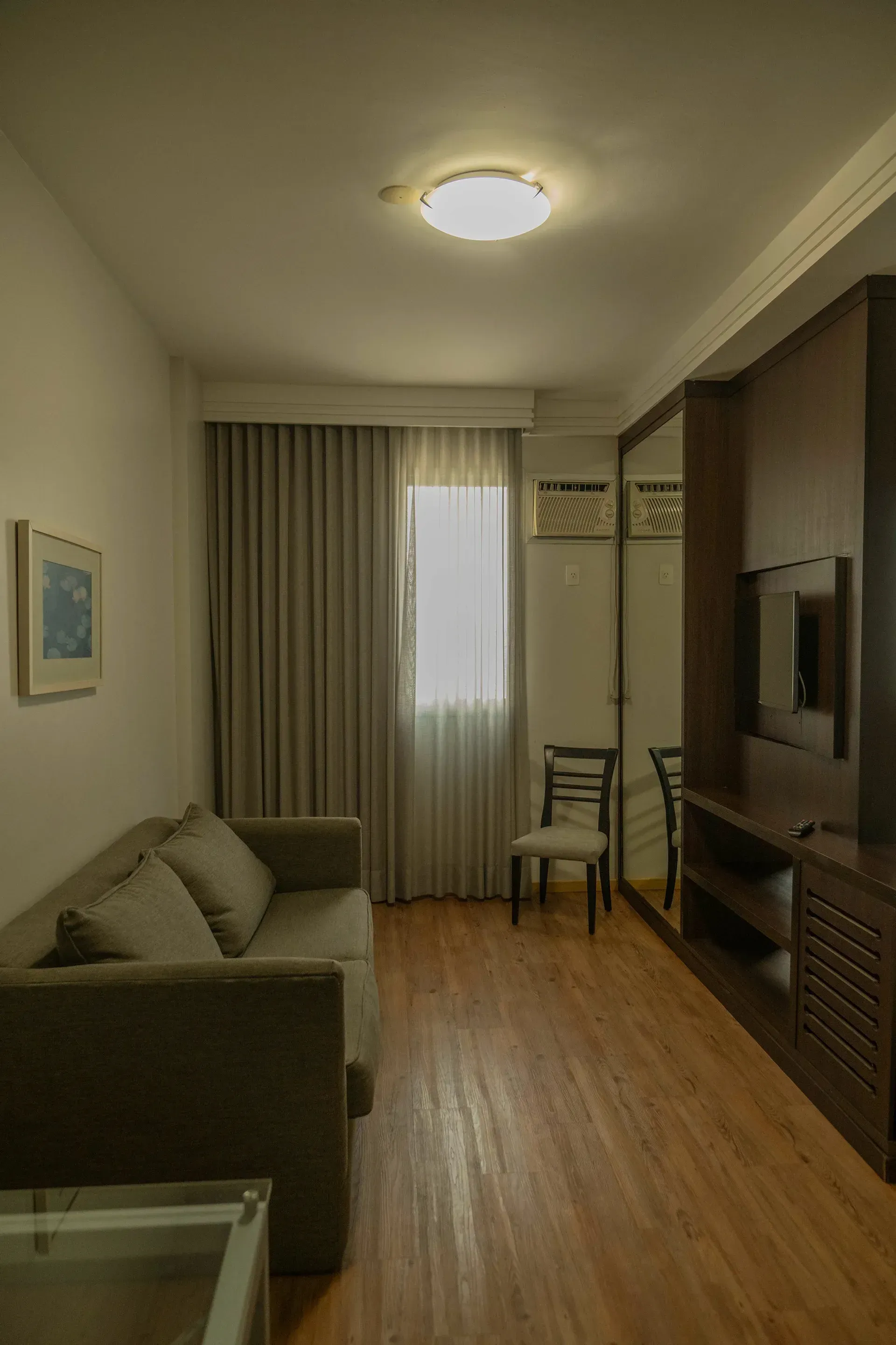 Uma sala de estar com sofá, cadeira, mesa e televisão.