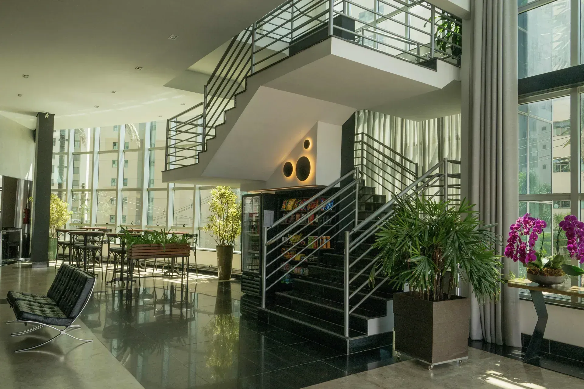 Um grande lobby com uma escada e muitas janelas