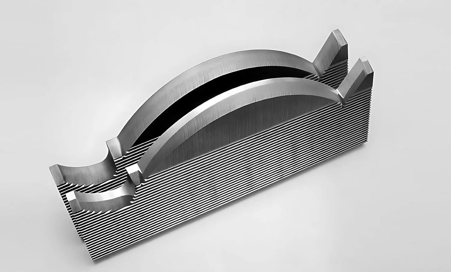 Gray metal paperweight with two curved sections, textured exterior.