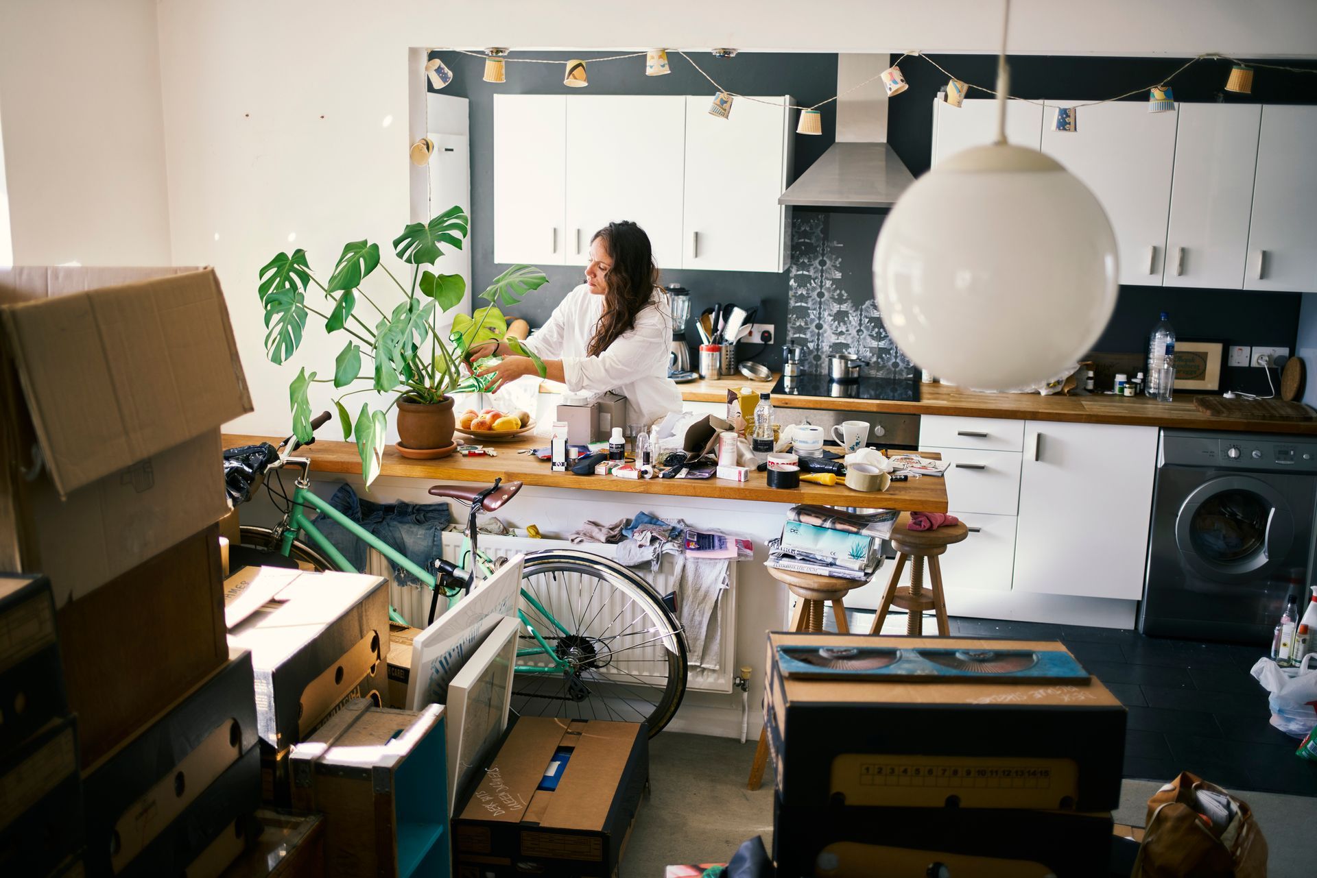 Woman watering her plants while packing items from her house.