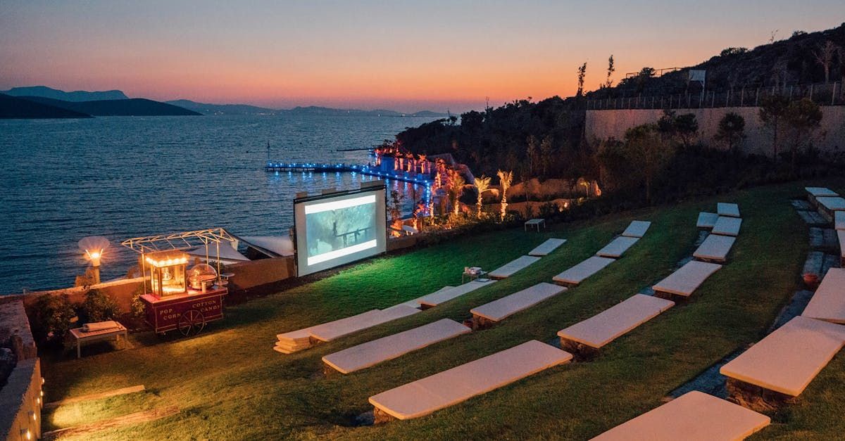 A large screen is sitting on top of a lush green field next to the ocean.