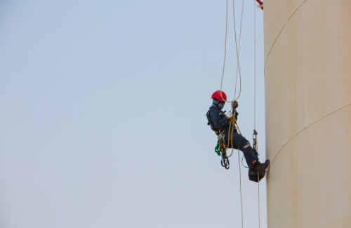 Un homme grimpe sur le côté d'un grand bâtiment.