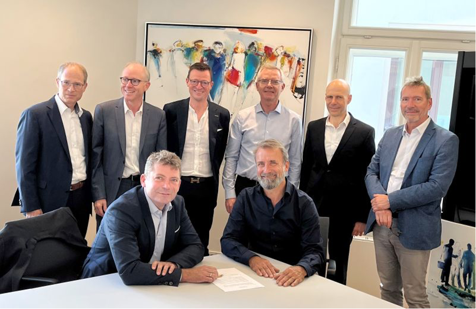 Un groupe d'hommes pose pour une photo assis autour d'une table.