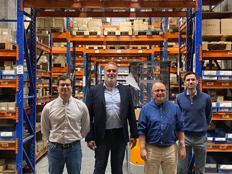 Un groupe d'hommes pose pour une photo dans un entrepôt.