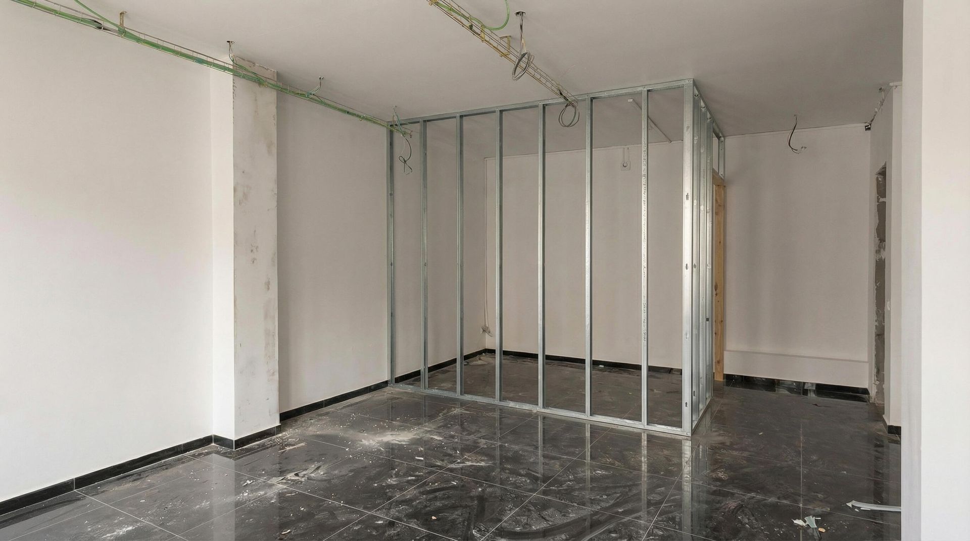 Habitación interior en construcción, con montantes metálicos a la vista, paredes y suelo sin terminar.