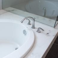 A white bathtub with a chrome faucet set installed on a white marble countertop.