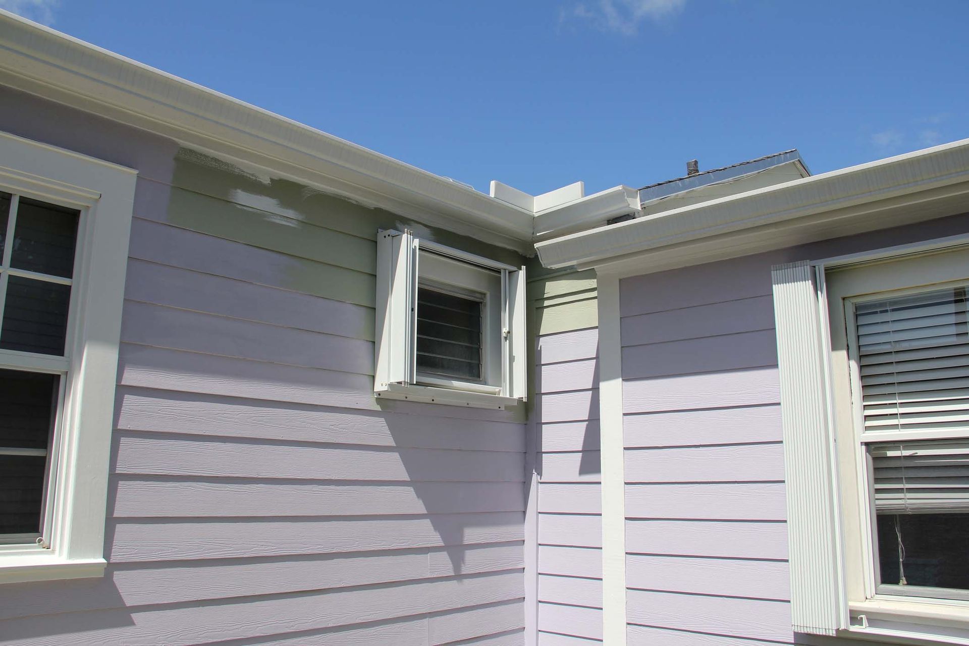 A purple house with white trim and shutters on the windows