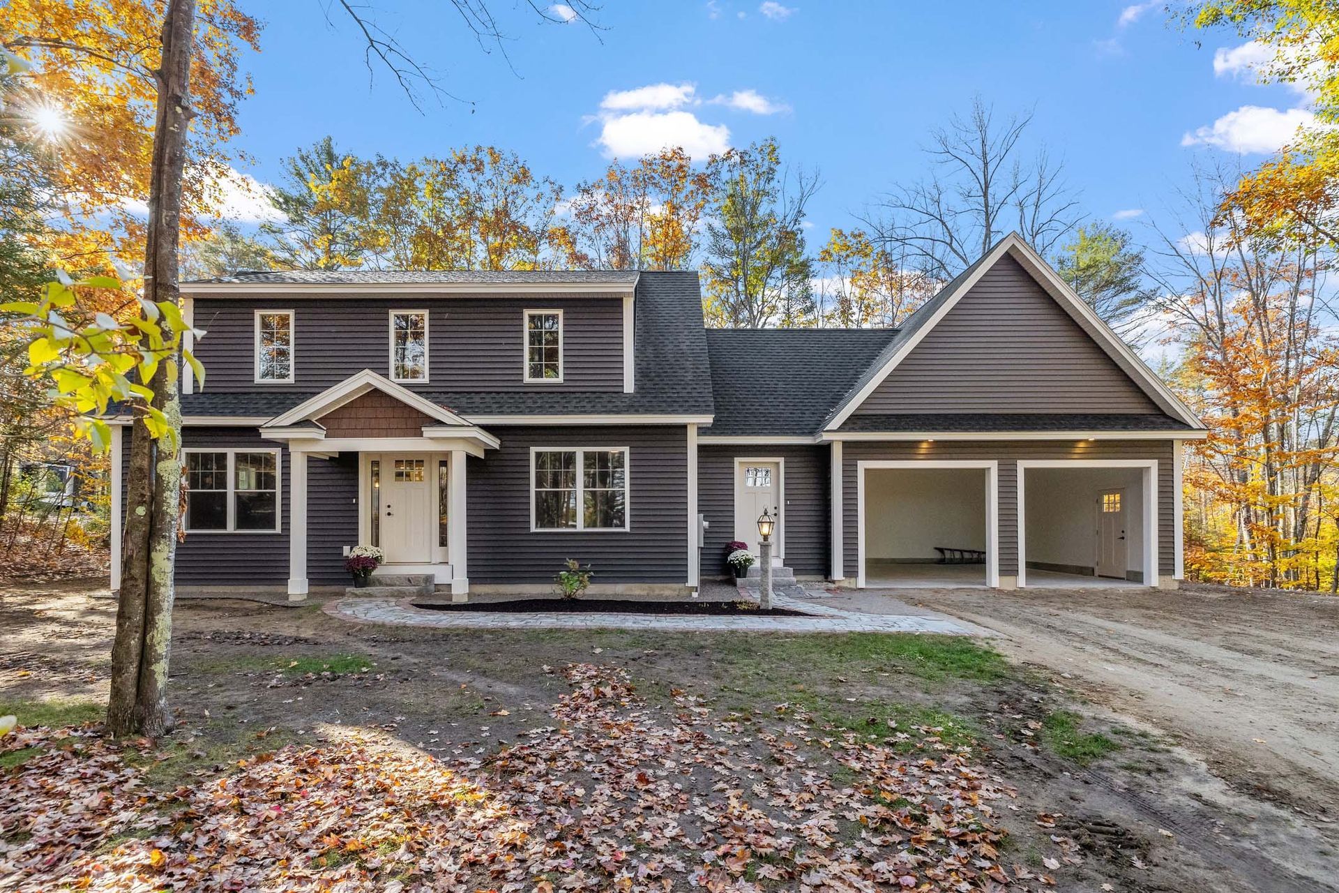 A large house is sitting on top of a dirt road in the middle of a forest.
