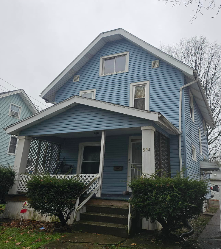 A blue house with a white roof and stairs