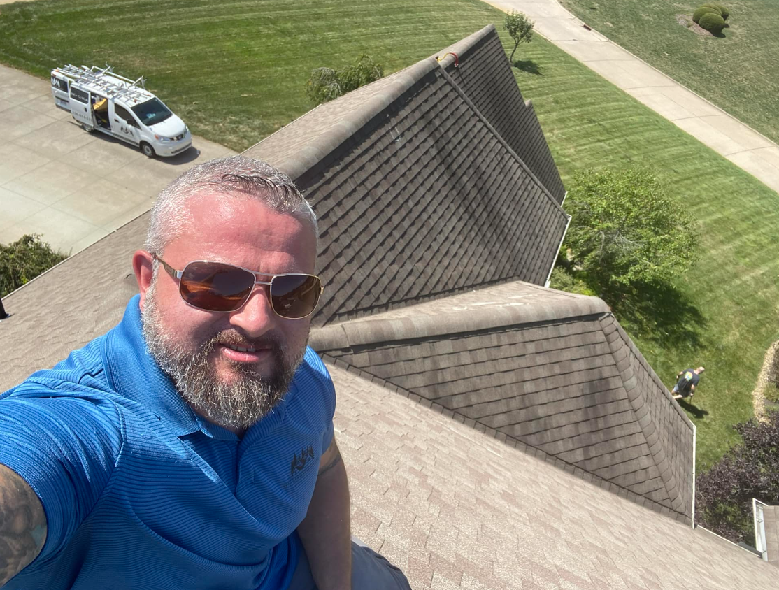 A man is taking a selfie on the roof of a house.