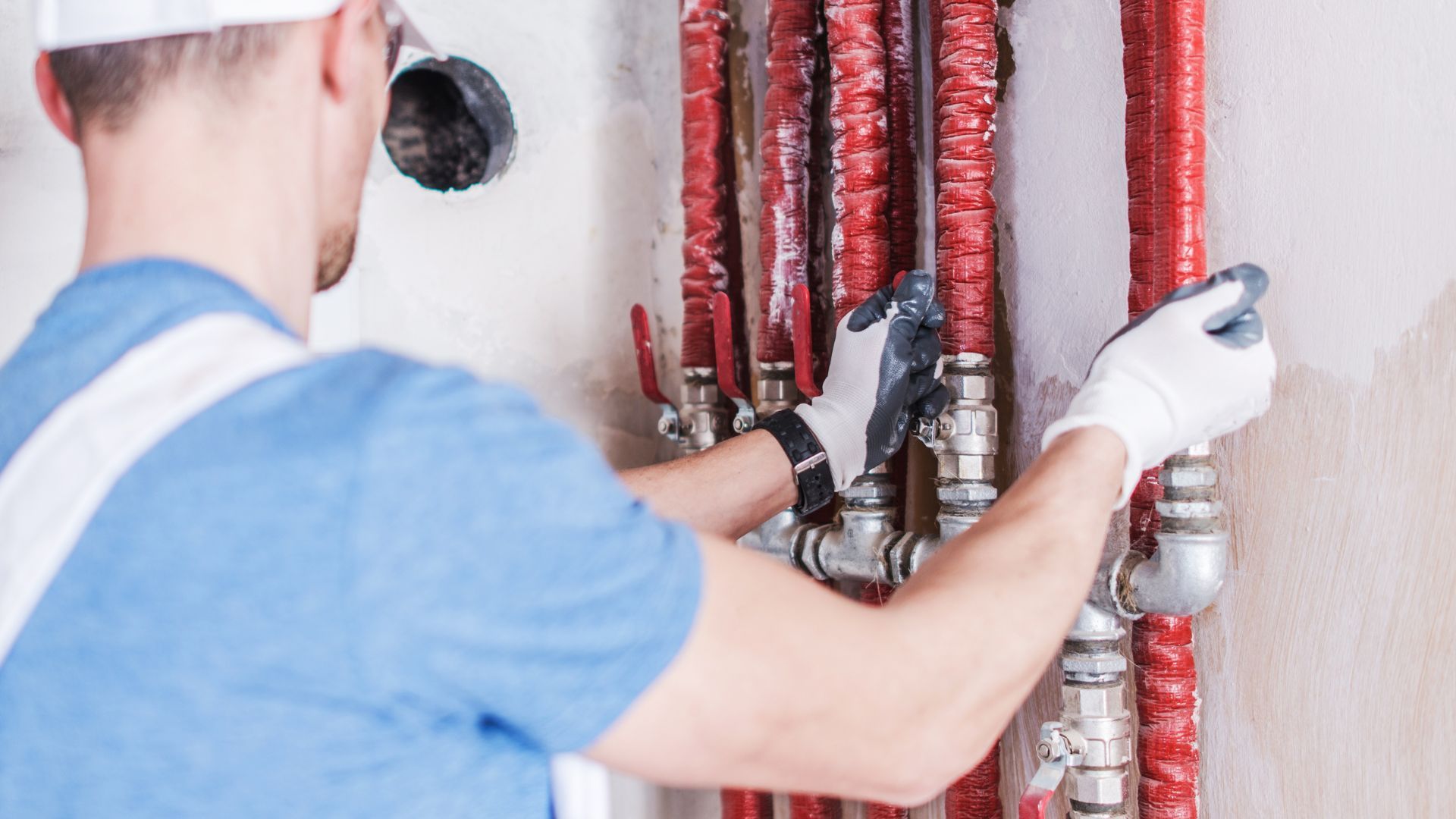 A man is working on a pipe with a pair of pliers.
