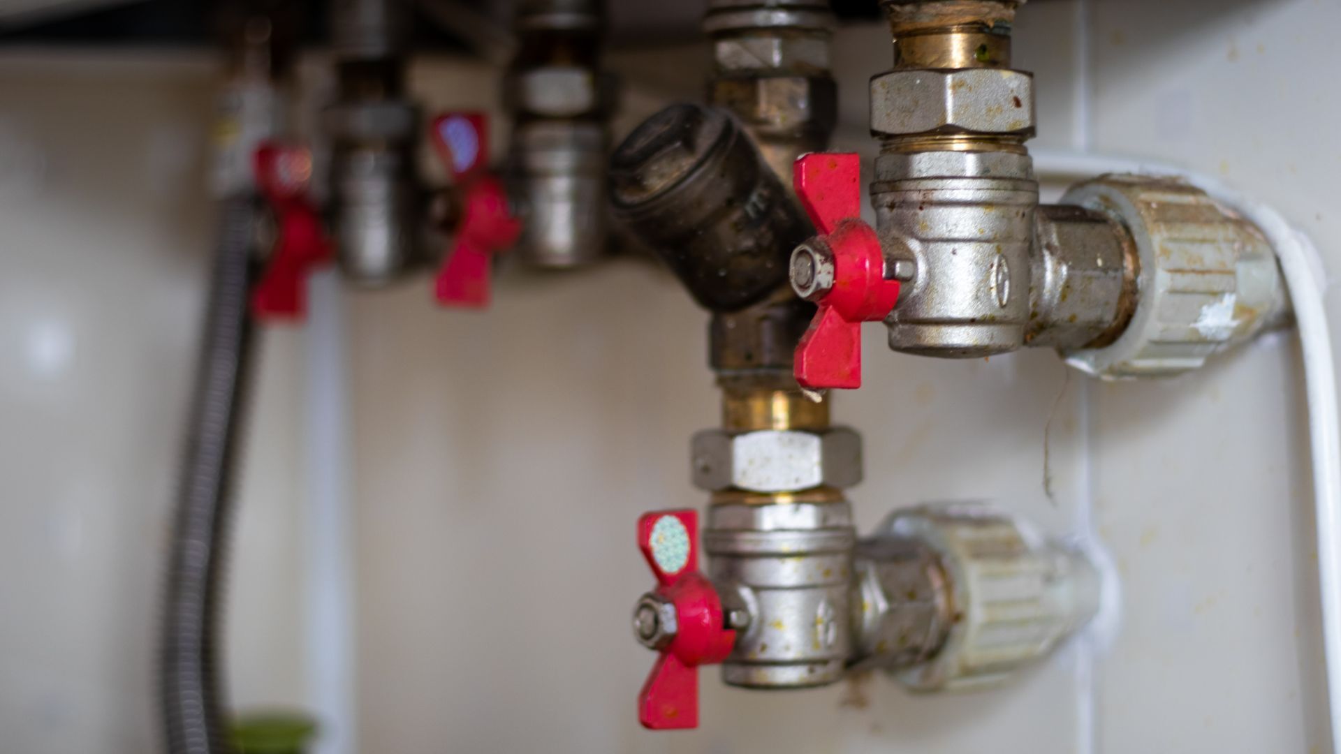 A close up of a water heater with red valves.