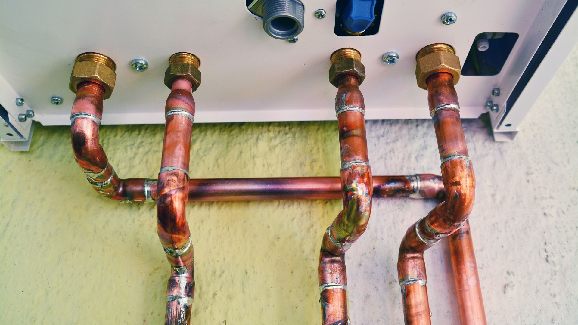 A close up of copper pipes attached to a wall