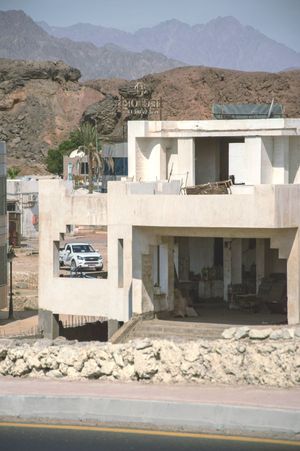 A white truck is parked in front of a building under construction