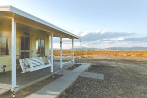 A yellow house with a white bench on the porch