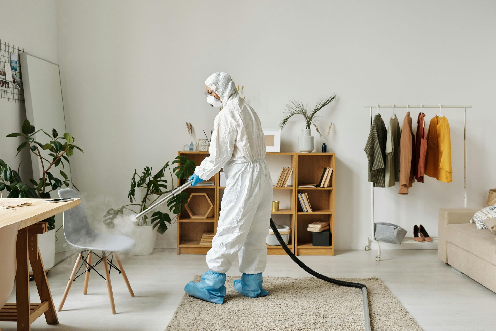 A man in a protective suit is spraying a room with a sprayer.