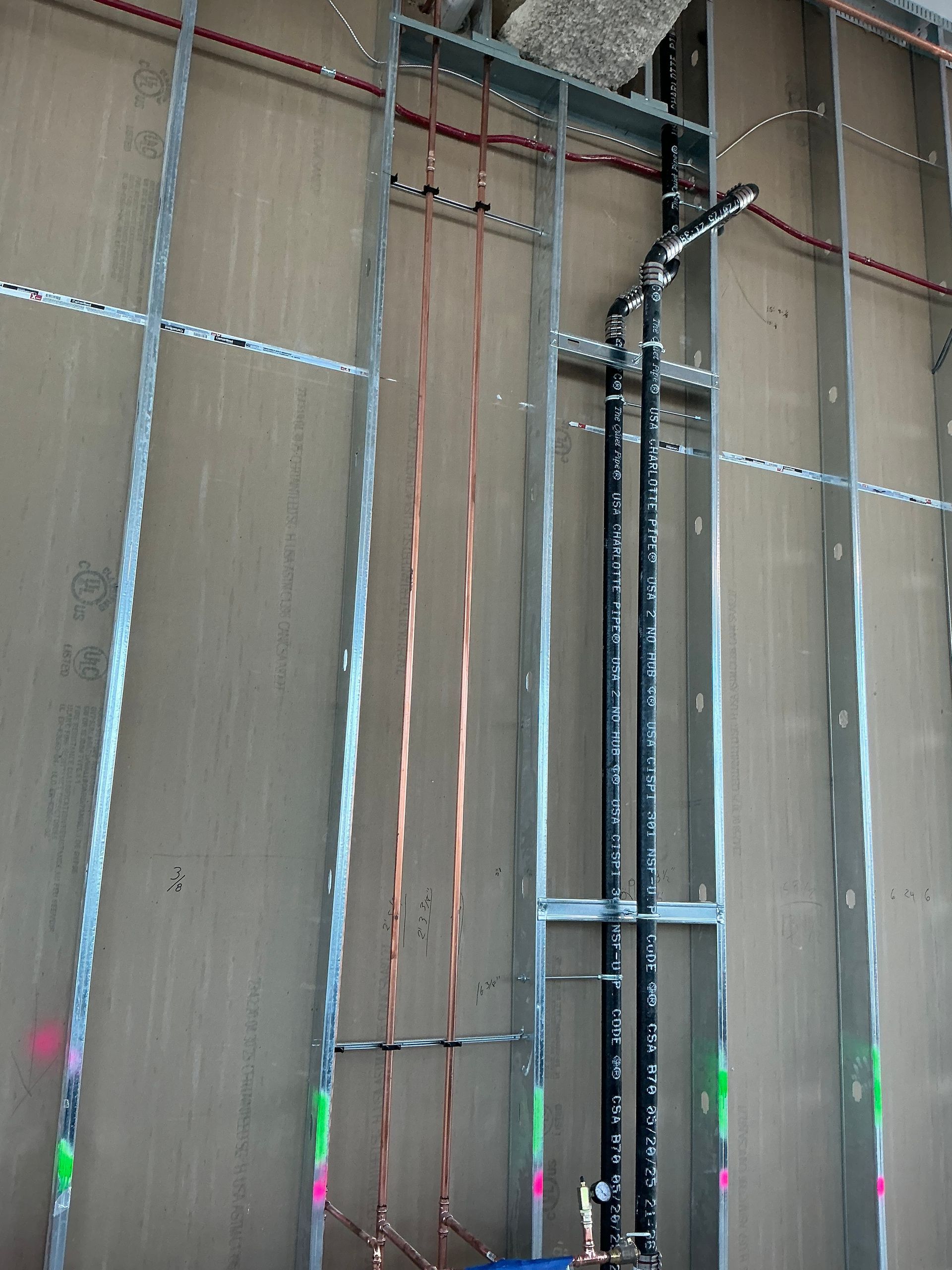 Plumber working under a kitchen sink, using a wrench. Tools and parts are scattered around the work area.