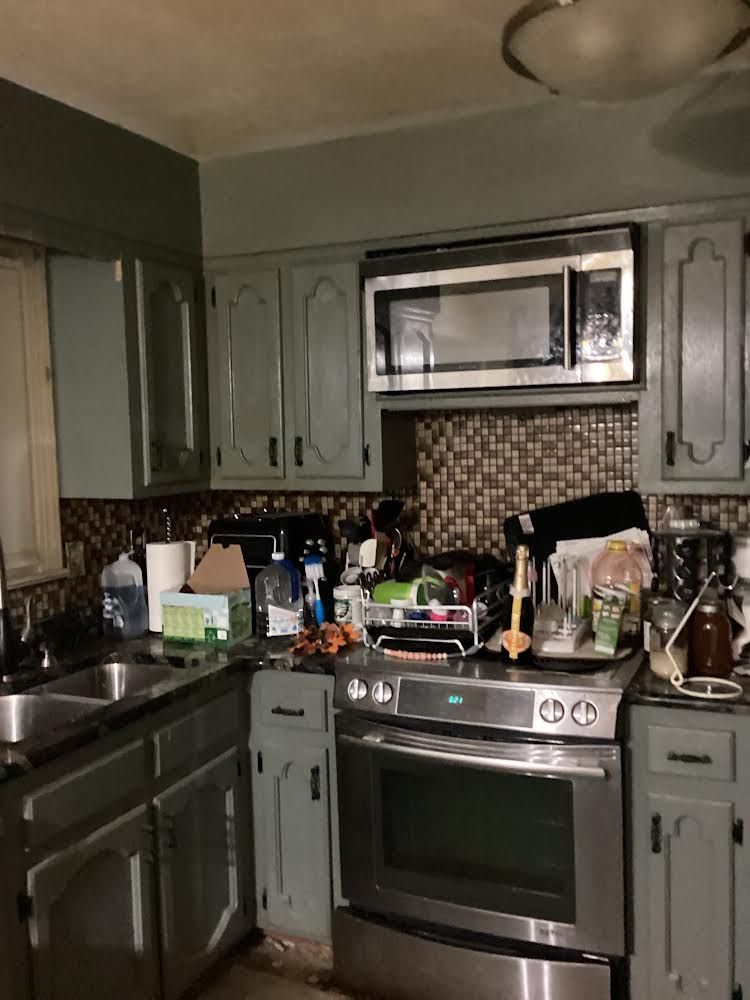 Kitchen remodel in progress, cabinets installed, backsplash tiling, tools on granite countertop.